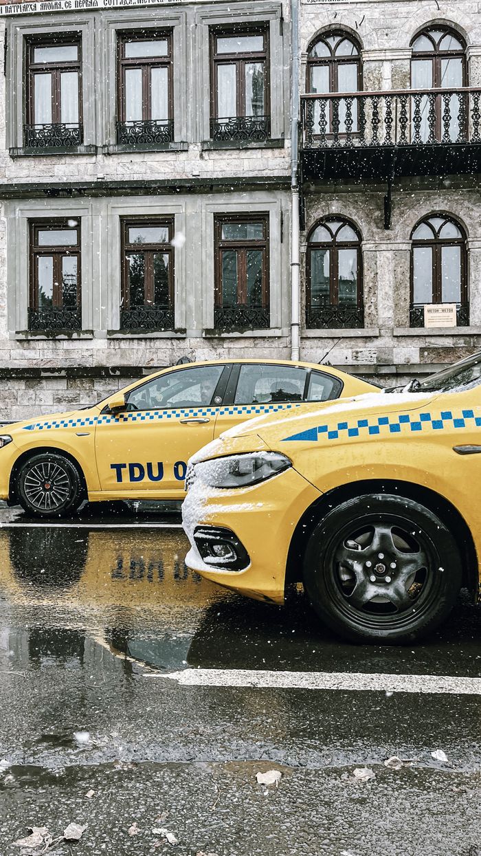Yellow taxis parked on a snowy street, vintage architecture backdrop.
